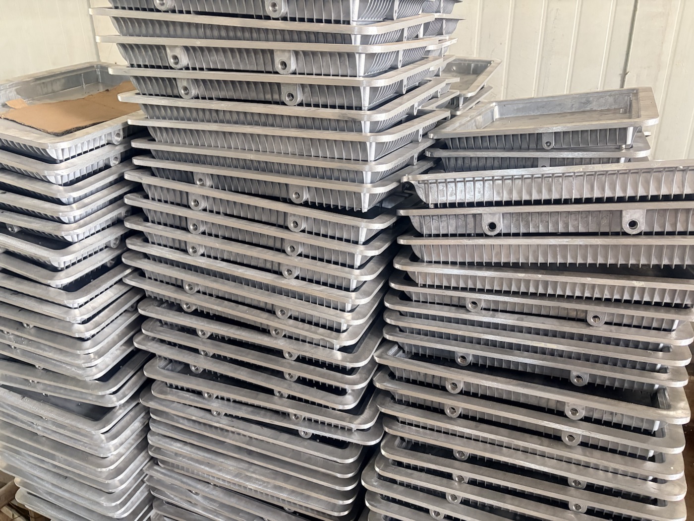 Stacks of raw aluminum die-cast LED work light housings before surface finishing